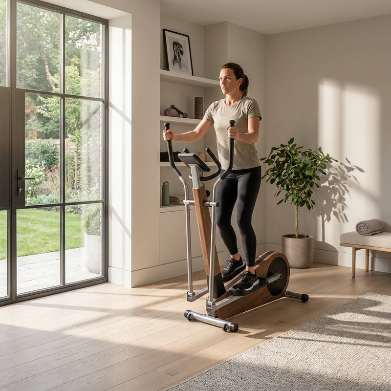 Volwassene traint op een crosstrainer in een modern, licht Nederlands interieur, met sportieve focus en een rustige thuisfitnesssfeer.